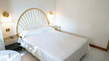 A single bed with a headboard, bedside tables, and wall-mounted lamps.