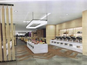 A spacious hotel lobby with a long reception desk, modern lighting fixtures, and a patterned floor.