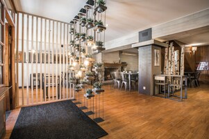 A modern interior with a wooden floor, a black carpeted entrance, and a dining area with metal chairs and a table.