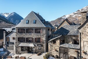 A stone building with a sloped roof, multiple windows, and a sign indicating it is a hotel.