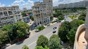 A multi-story residential building with a central courtyard, surrounded by greenery and a busy street. - Green Apartment No 63 (Bucharest)