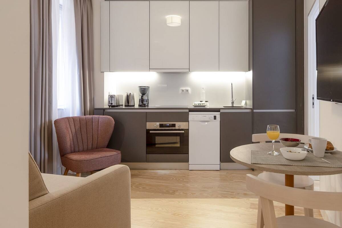A modern kitchen with a dining area, a sofa, and a chair.