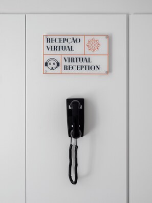 A white wall with a sign indicating a virtual reception area and a telephone. - Lisbon Serviced Apartments Santos (Lisbon)
