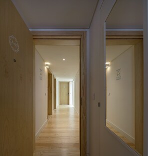A hallway with wooden floors and doors, each marked with a number and a symbol. - Lisbon Serviced Apartments Santos (Lisbon)