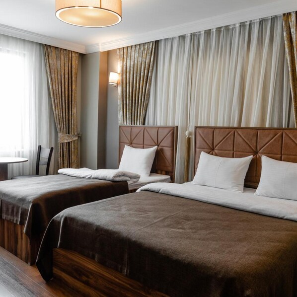 A hotel room with two beds, a wooden headboard, and a large window with curtains. - Madame Roza (Istanbul)