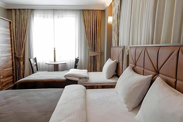 A hotel room with two beds, a small table, and a chair. - Madame Roza (Istanbul)