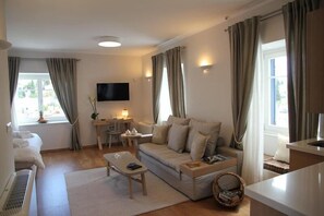 Ett vardagsrum med en soffa, ett soffbord, en tv och ett litet bord med en lampa.