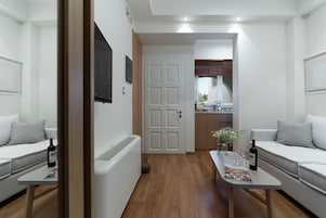 A modern living room with a sofa, a coffee table, and a door leading to a kitchen.