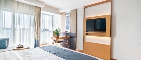 Una camera d'albergo moderna con un letto grande, una scrivania, una sedia, una televisione e una finestra con tende.