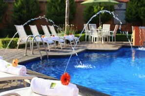 A swimming pool with lounge chairs and a table, surrounded by greenery. - GS Quinto Sol de Teotihuacan (Teotihuacan)