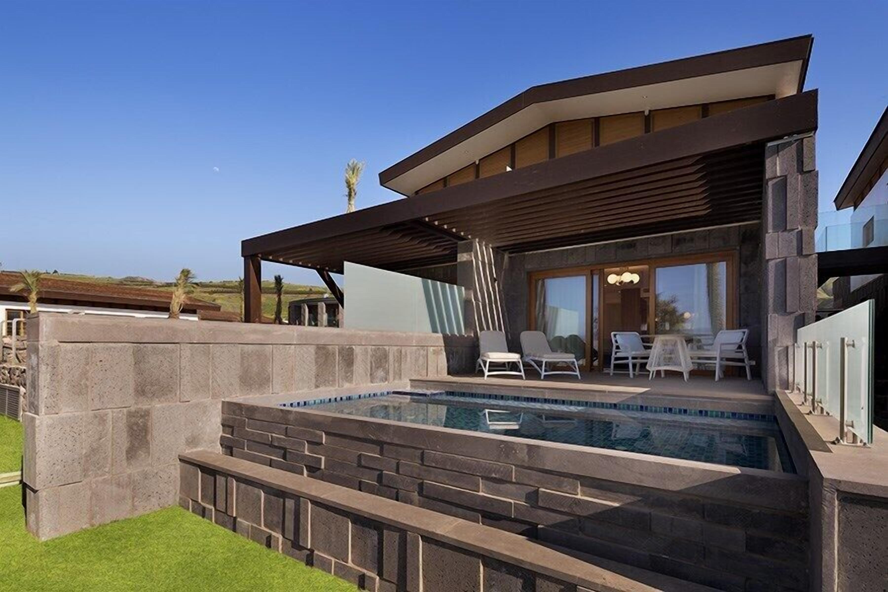 A modern house with a swimming pool, outdoor seating, and a covered patio.