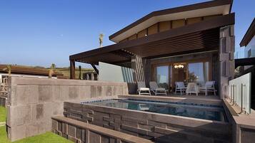A modern house with a swimming pool, outdoor seating, and a covered patio.