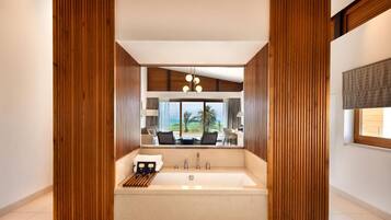 A modern bathroom with a large bathtub, a view of the outdoors, and wooden paneling.