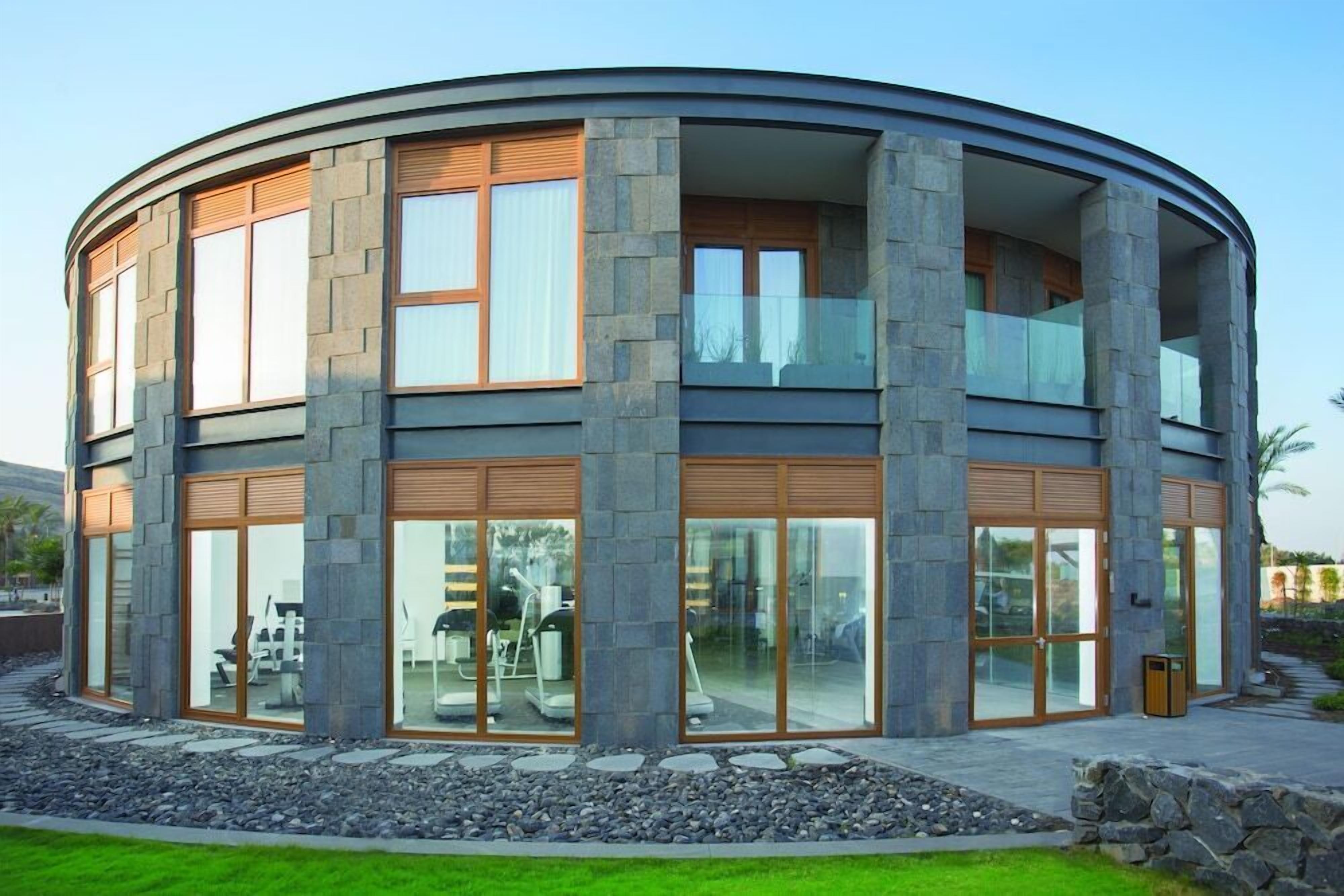 A modern, multi-story building with large glass windows and a stone facade.