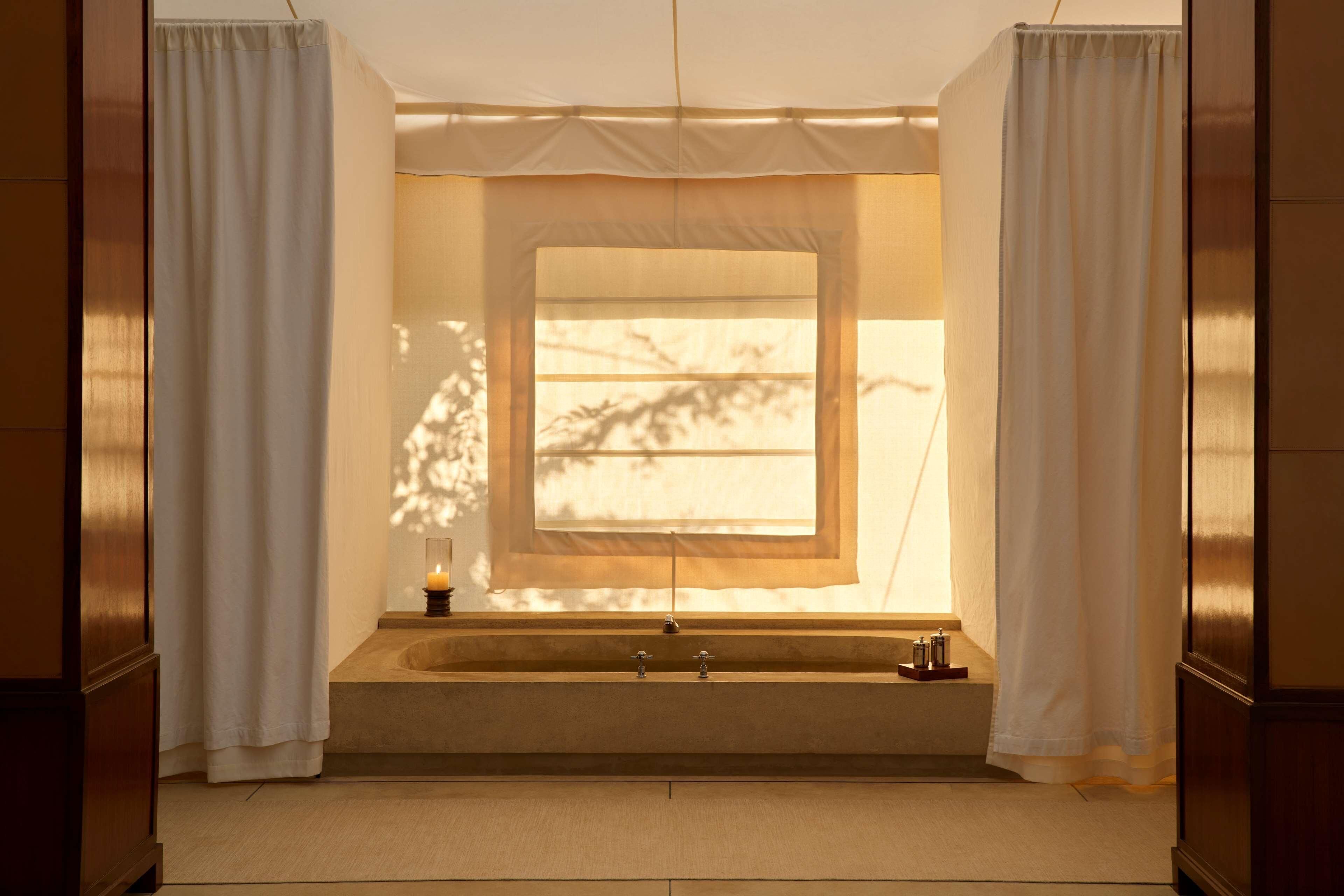 A bathroom with a bathtub, a window, and a candle on the side.