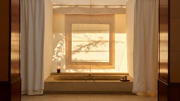 A bathroom with a bathtub, a window, and a candle on the side.