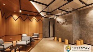 A modern hotel lobby with wooden paneling, grey upholstered chairs, and a 'TOWER' sign on the wall. - Nidoz Residences Luxury Apartments (Kuala Lumpur)