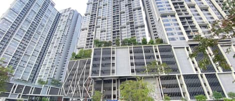 A modern high-rise building with multiple floors, large windows, and a mix of balconies and terraces.