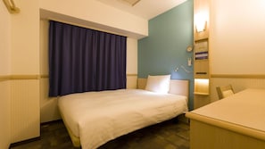 A hotel room with a bed, a desk, a chair, a window with curtains, a wall clock, and a nightstand with a lamp.