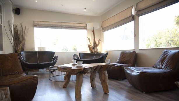 A modern living room with a wooden coffee table, leather sofas, and a large window providing natural light. - Hotel Des Sables Dor (Cucq)