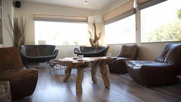 A modern living room with a wooden coffee table, leather sofas, and a large window providing natural light.