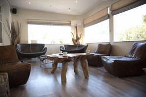 A modern living room with a wooden coffee table, leather sofas, and a large window providing natural light. - Hotel Des Sables Dor (Cucq)
