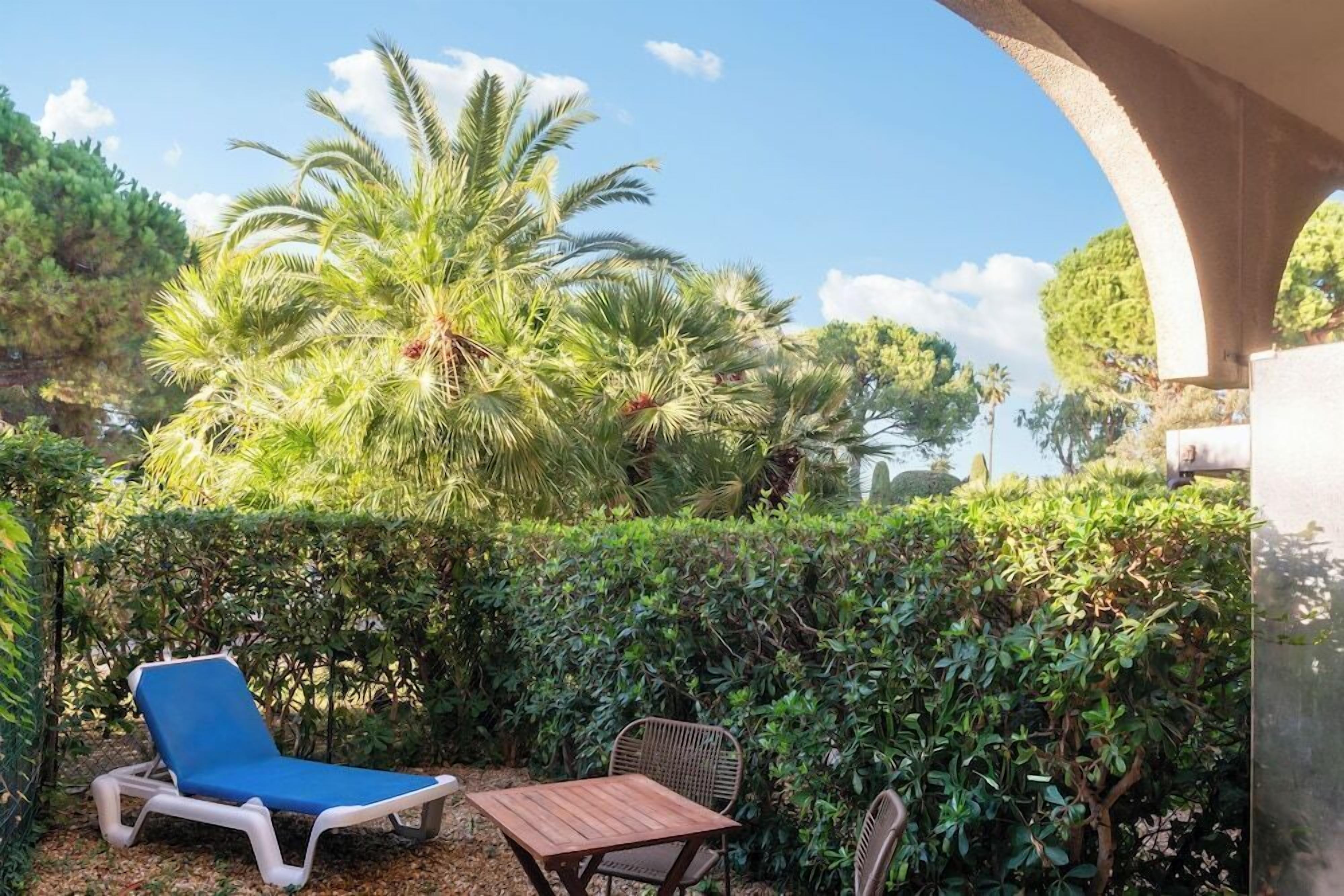 A patio with a blue lounge chair, a wooden table, and a wicker chair.