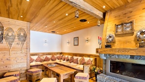 A cozy log cabin interior with a wooden bench seating area, a fireplace, and a stone wall.