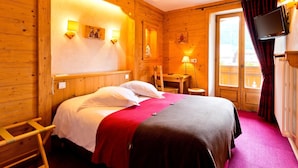A wooden room with a bed, a desk, and a TV.