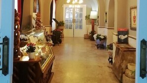 A corridor with arched ceilings and a chandelier. There are display cases with items on the left and a counter with a sign on the right. - Xabier Hotel Javier (Javier)