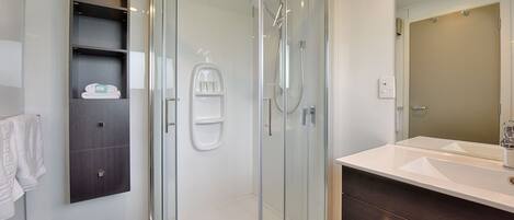 A modern bathroom with a glass-enclosed shower, a white sink, and a dark wooden vanity.