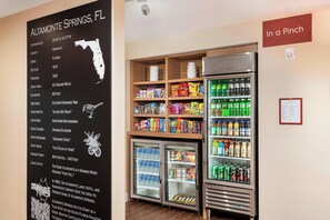A hotel room with a blackboard displaying local information about Altamonte Springs, FL, and a refrigerator stocked with beverages and snacks. - Towneplace Suites by Marriott Orlando Altamonte Springs/maitland (Altamonte Springs)