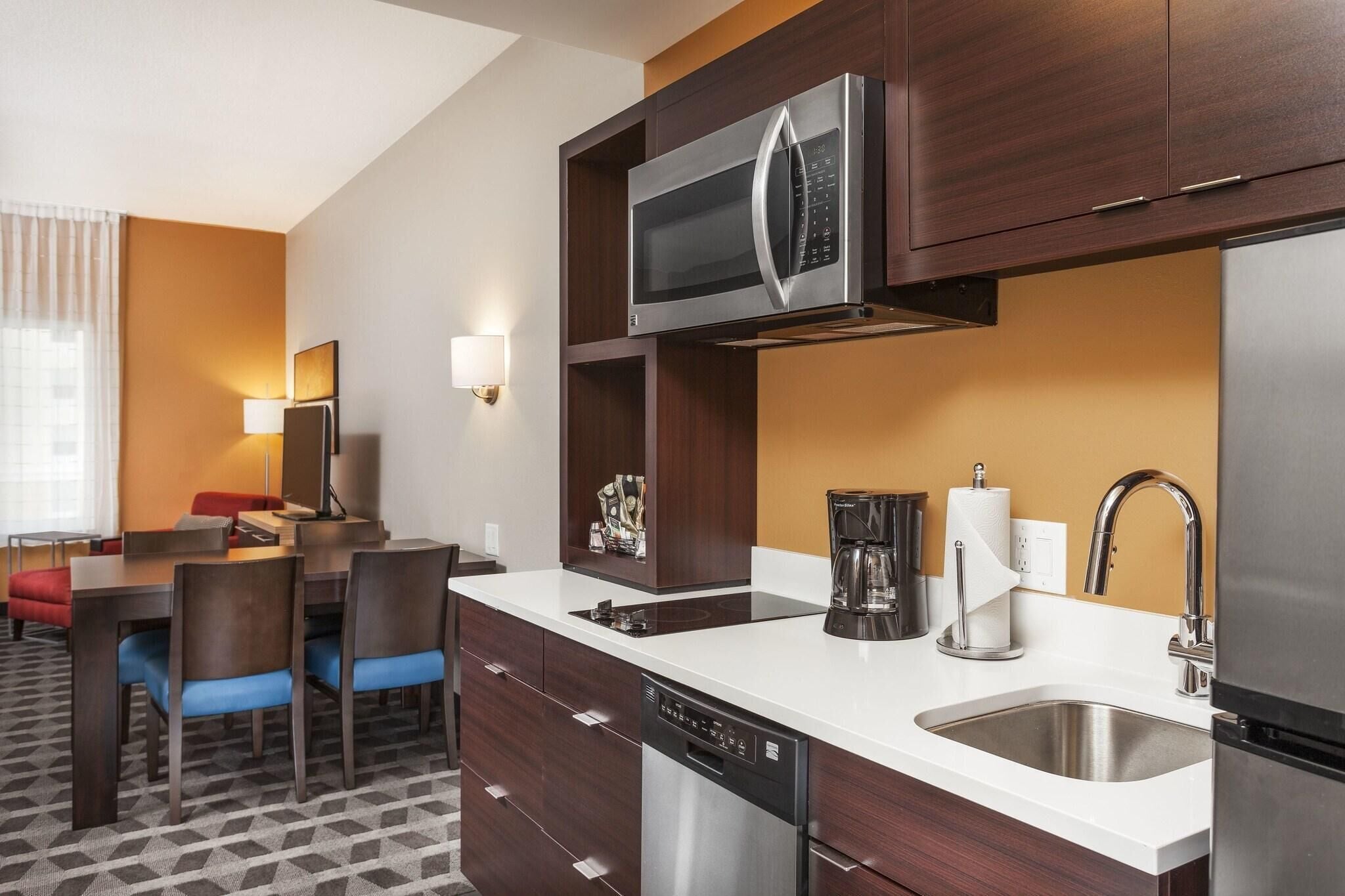 A modern hotel kitchen with a microwave, coffee maker, and dishwasher.