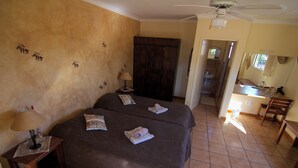 A hotel room with two beds, a wooden wardrobe, a bathroom visible through an open door, and a small kitchenette area. - Etango Ranch Guest Farm (Windhoek)