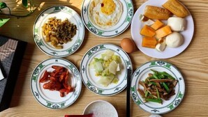 A wooden table with various dishes including fried egg, dumplings, and vegetables. - Greentree Inn Shanghai West Huaxia Road Subway Station Hotel (Shanghai)