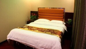 Une chambre d’hôtel avec un lit, une table de chevet et une plante en pot.