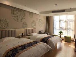 Una habitación de hotel moderna con dos camas, una pequeña zona de estar y un ventanal grande con cortinas.