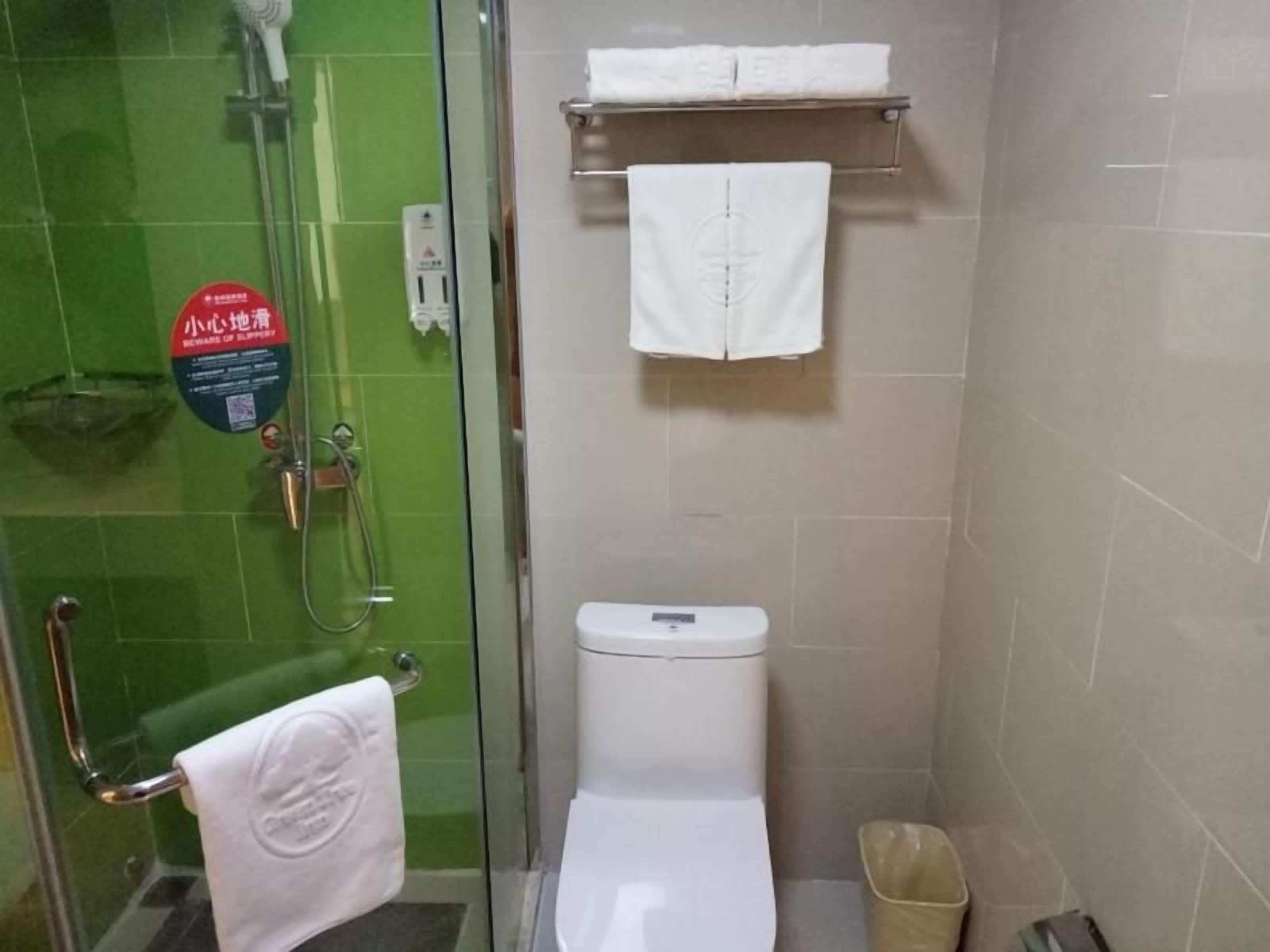 A bathroom with a glass shower enclosure, a toilet, and a towel rack.