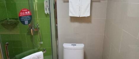 A bathroom with a glass shower enclosure, a toilet, and a towel rack.