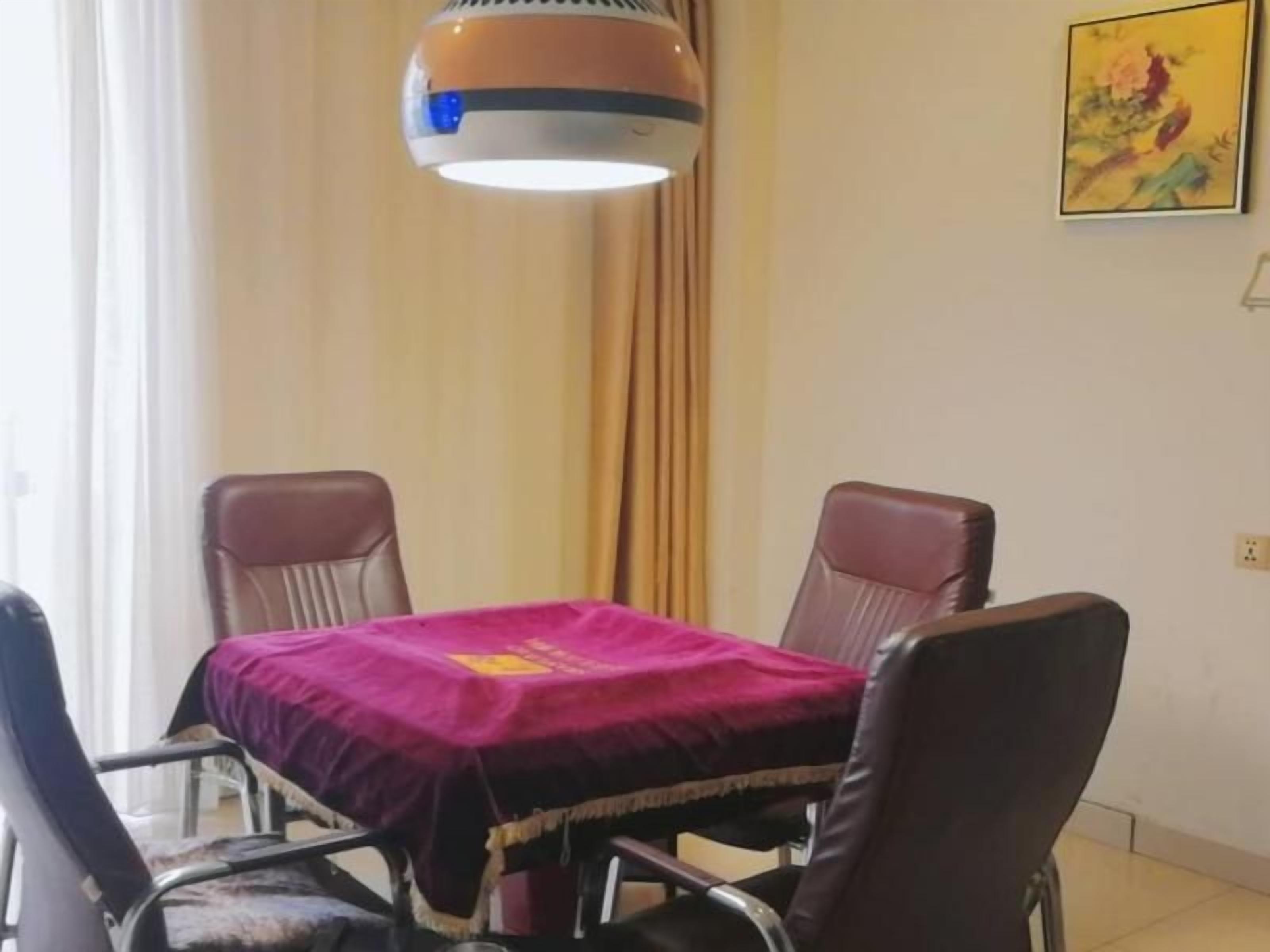 A dining area with a table covered by a purple cloth, surrounded by four leather chairs.