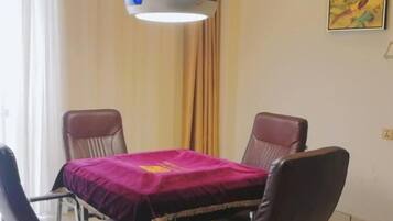 A dining area with a table covered by a purple cloth, surrounded by four leather chairs.