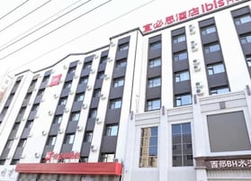 Un hotel de varios pisos con fachada moderna, unidades de aire acondicionado y un toldo rojo.