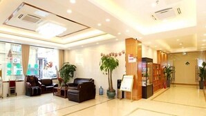 A hotel lobby with a reception desk, seating area, and a large potted plant.