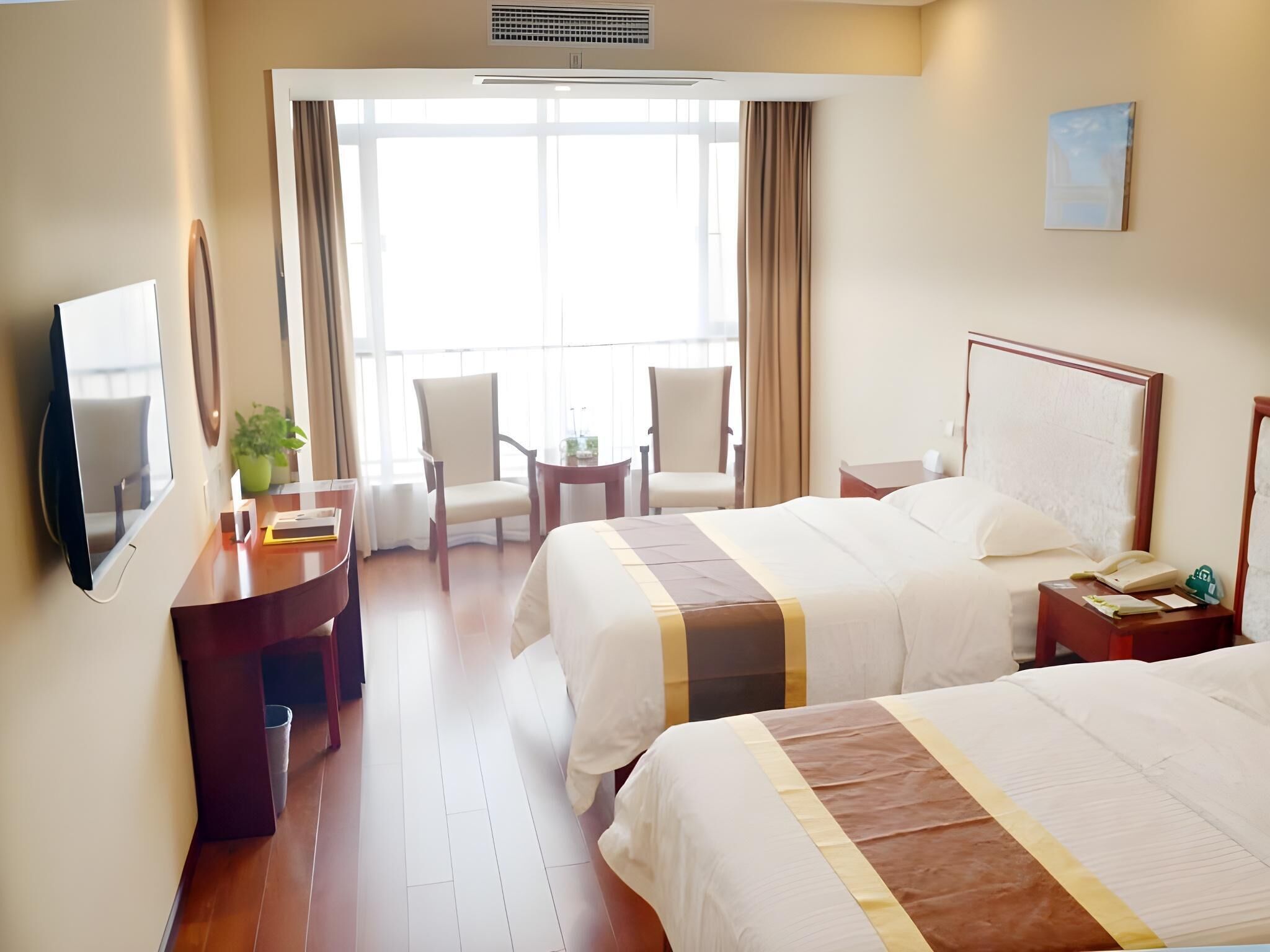 A hotel room with two beds, a desk, a chair, a TV, and a balcony with curtains.