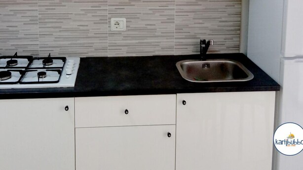 A kitchen with white cabinets, a black countertop, a stainless steel sink, and a gas stove. - Kartibubbo Beach Resort (Campobello di Mazara)