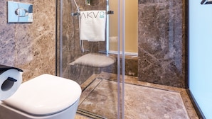 A modern bathroom with a glass-enclosed shower, a white toilet, and marble flooring. - Akvo (Hong Kong Island)