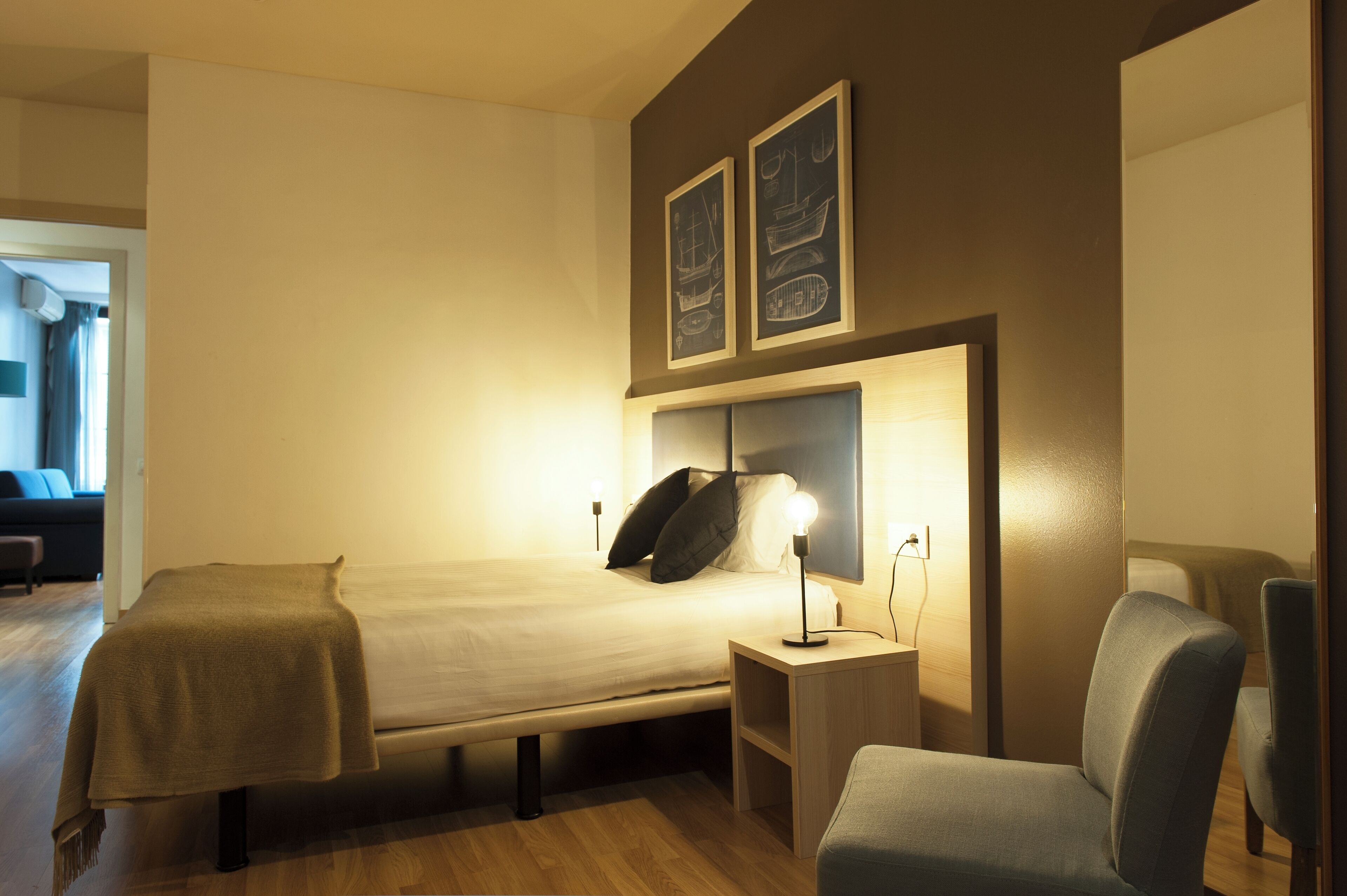 A hotel room with a bed, bedside tables, a chair, and artwork on the wall.