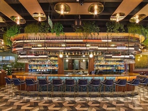 Un bar con distribución circular, varias zonas de estar y una gran variedad de botellas.