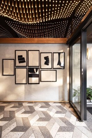 A modern interior with a patterned floor, a ceiling with hanging lights, and framed artwork on the wall. - Hyde Johannesburg Rosebank (Johannesburg)