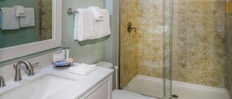 Une salle de bain équipée d’une douche, de toilettes, d’un lavabo et d’un miroir.